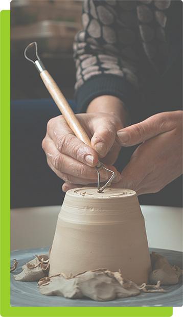 Artist creating art on pottery wheel using tool.